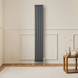 Sleek anthracite grey oval single column radiator, measuring 1600 x 240mm, mounted on a light wall in a cozy room setting