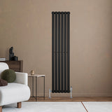 Sleek black oval single column radiator mounted on a textured wall, complementing a modern living room with neutral tones