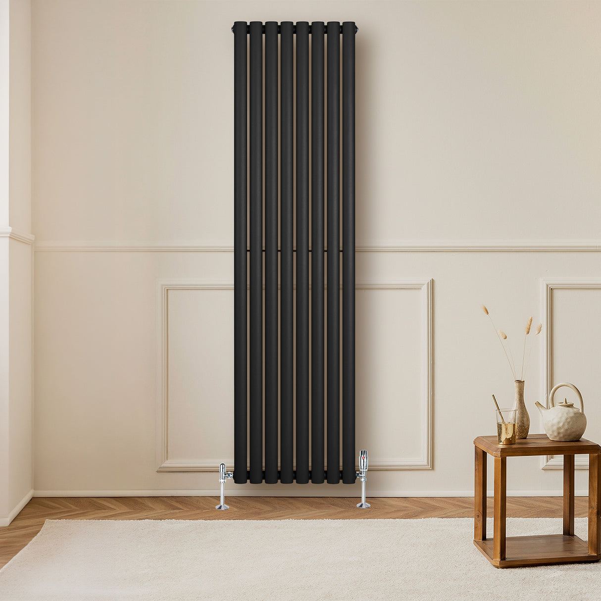 Sleek black oval single column radiator, 1800 x 480mm, mounted on a light wall, complementing a wooden table and decor elements