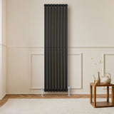 Sleek black oval single column radiator, 1800 x 480mm, mounted on a light wall, complementing a wooden table and decor elements