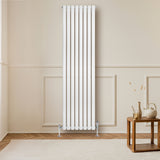 Sleek white oval single column radiator, 1800 x 480mm, mounted on a wall, complementing a modern interior with wooden flooring and decor