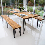 Stylish wooden dining table with hairpin legs, accompanied by matching benches, set in a bright, modern space with greenery outside