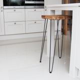 Grey 10mm hairpin leg feet protectors on a wooden table leg, enhancing stability and protecting flooring in a modern kitchen setting