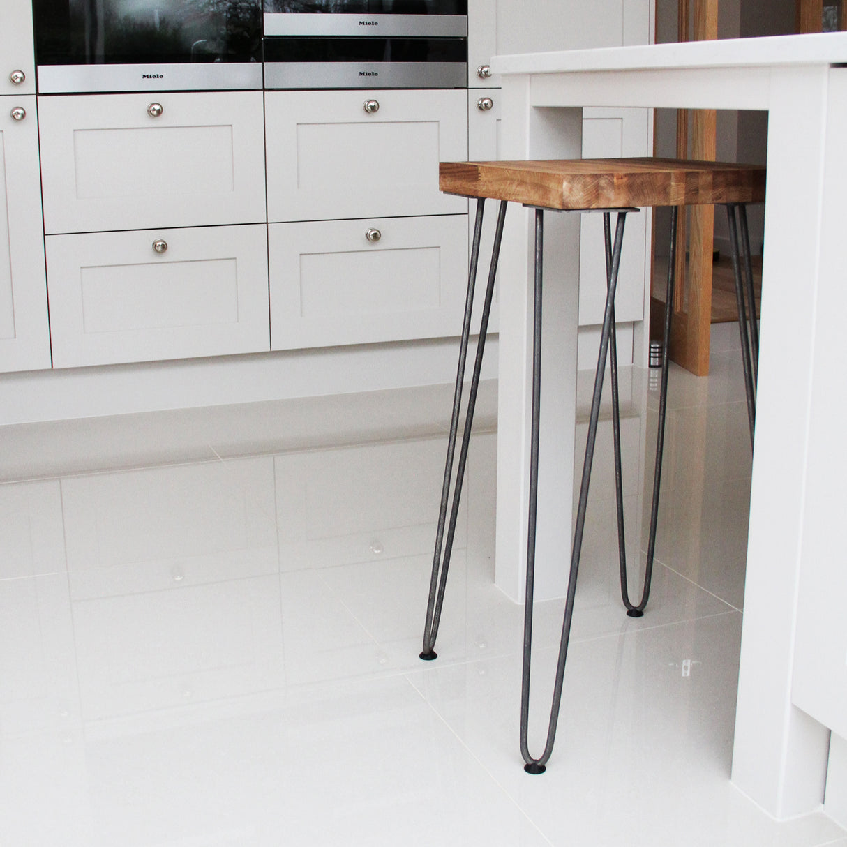 Black 12mm hairpin leg feet protectors on a wooden table, showcasing sleek design and sturdy metal construction in a modern kitchen setting