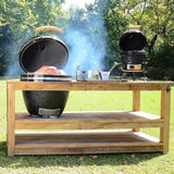 Kamado charcoal BBQ grill on a wooden table, with smoke rising, showcasing a sleek black ceramic design and grilling accessories