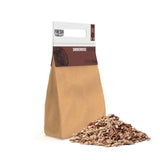 Brown paper bag of Fresh Grills hickory wood chips, with a pile of chips beside it, ideal for BBQ grills and smokers