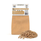 Natural oak wood pellets in a mound, packaged in a brown paper bag with clear instructions for BBQ grill and pizza oven use
