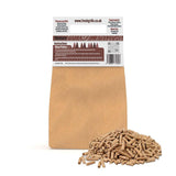 Hickory wood pellets in a pile beside a brown kraft bag, ideal for BBQ grills, pizza ovens, and outdoor smokers, enhancing flavor